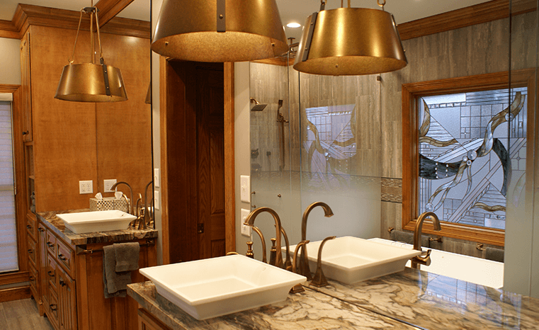 A bathroom with two sinks and gold fixtures.