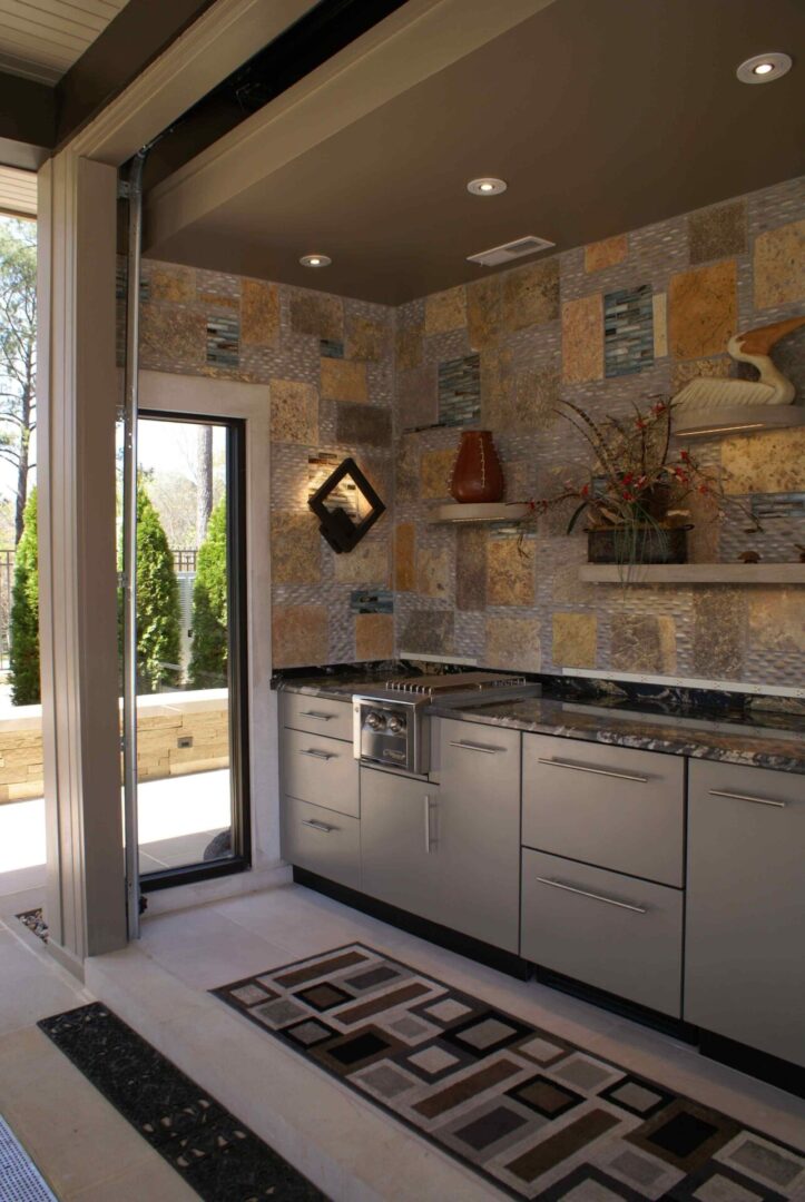 A kitchen with a tile wall and a sliding glass door.
